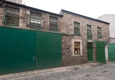 an old brick building with green doors on a street at Apartment Thistle Lane in Edinburgh