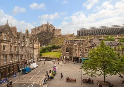 a city street with buildings and a castle in the background at Castle Suite 1 Old Town in Edinburgh