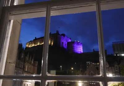 a window view of a castle lit up at night at Castle Suite 1 Old Town in Edinburgh