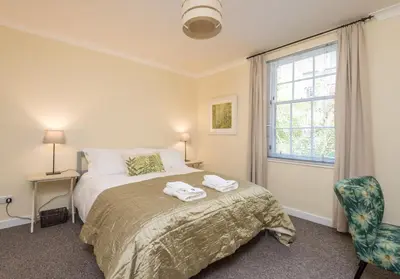a bedroom with a bed and a window and a chair at Castle Suite 3 Old Town in Edinburgh