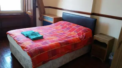 a bedroom with a bed with a green pillow on it at Broompark House in Glasgow
