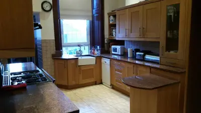 a kitchen with wooden cabinets and a counter top at Broompark House in Glasgow
