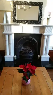 a fireplace with a flower in a vase on a table at Broompark House in Glasgow