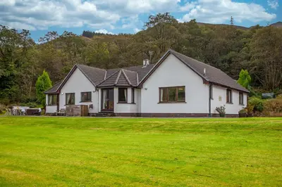 a white house with a green lawn at Wildwood Cottage with Hot Tub in Glencoe