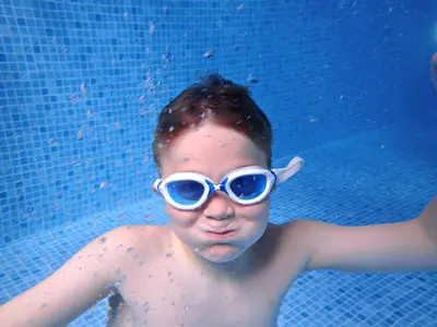 a young boy wearing goggles in a swimming pool at Loch Linnhe Waterfront Lodges with Hot Tubs in Glencoe
