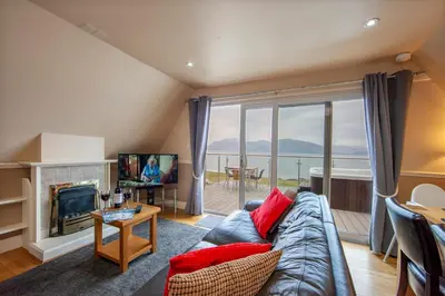 a living room with a couch and a large window at Loch Linnhe Waterfront Lodges with Hot Tubs in Glencoe