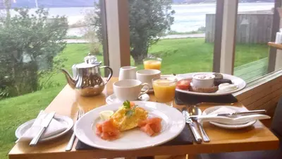 a table with a plate of breakfast food and a window at Loch Linnhe Waterfront Lodges with Hot Tubs in Glencoe