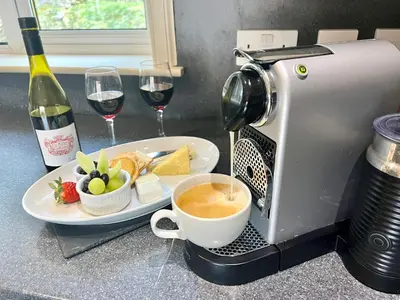 a coffee maker and a plate of food and two glasses of wine at Glenachulish Bay with Hot Tub in Glencoe