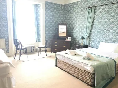 a bedroom with a bed with a teddy bear on it at Cannon House Guest House in Rothesay