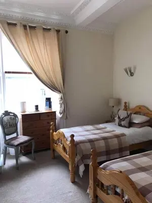 a bedroom with two beds and a chair and a window at The Stag Head Hotel in Edinburgh