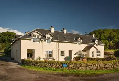a large white house with a stone wall at Melfort Village in Oban