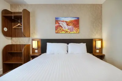 a bedroom with a large bed with white sheets at Highland Gate, Stirling by Marston's Inns in Stirling