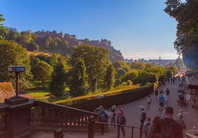a group of people walking down a street with a castle in the background at Edinburgh Castle Suite - The Edinburgh Address in Edinburgh