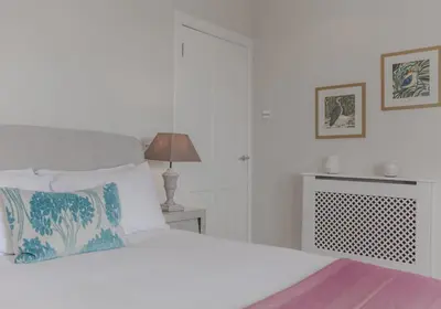 a white bedroom with a bed and a lamp at The Skyline - The Edinburgh Address in Edinburgh