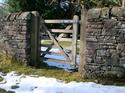 a wooden gate in a stone wall with snow at Strathendrick House Magnificent property with Garden in Drymen