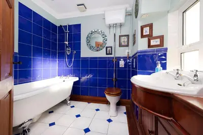a blue tiled bathroom with a tub and a toilet at Strathendrick House Magnificent property with Garden in Drymen