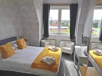 a small room with a bed and a desk and two windows at Brig O'Doon Guest House in Edinburgh