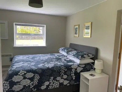 a bedroom with a bed with a blue comforter and a window at Woodside Cottage Self Catering in Kinbuck