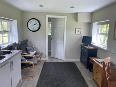 a kitchen with a clock on the wall and chairs at Woodside Cottage Self Catering in Kinbuck