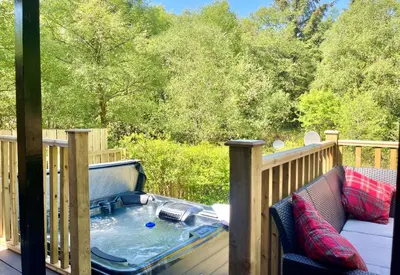 a hot tub on the deck of a house at Ash Lodge in Benmore