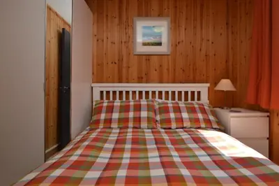 a bedroom with a bed with a checkered blanket at Ash Lodge in Benmore
