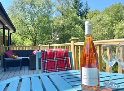 a bottle of wine sitting on a table with a wine glass at Ash Lodge in Benmore