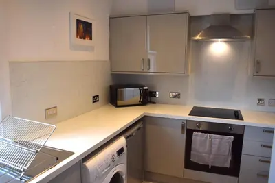 a kitchen with a washing machine and a microwave at Kelpies Serviced Apartments - Wallace in Falkirk