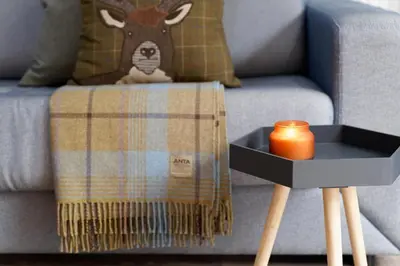 a couch with a blanket and a candle on a table at Riverside West End Apartment in Glasgow
