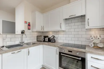 a white kitchen with white cabinets and a sink at The Wee Thistle in Edinburgh