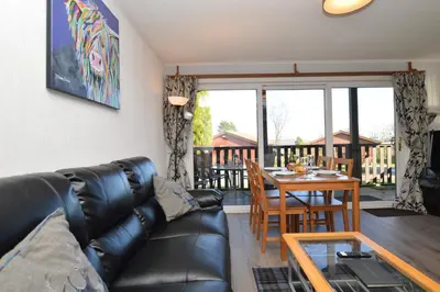 a living room with a leather couch and a table at Holy Loch Lodge in Hunters Quay