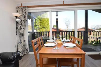 a dining room table with chairs and a large window at Holy Loch Lodge in Hunters Quay