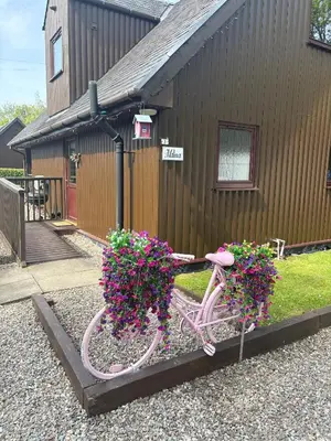 a pink bike with flowers in front of a building at La Fortuna Lodges in Stirling