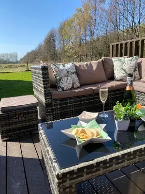 a patio table with a couch and a glass of wine at La Fortuna Lodges in Stirling