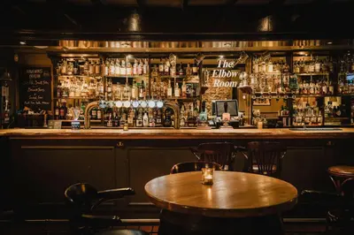 a bar with a wooden table and chairs at The Inverkip Restaurant, Bar & Hotel in Inverkip