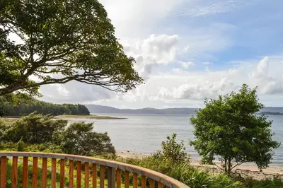 a view of a beach with a wooden fence at Oystershell Lodge in Otter Ferry