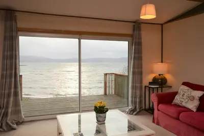 a living room with a large window with a view of the ocean at Oystershell Lodge in Otter Ferry