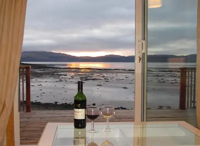 a bottle of wine sitting on a table with two glasses at Oystershell Lodge in Otter Ferry