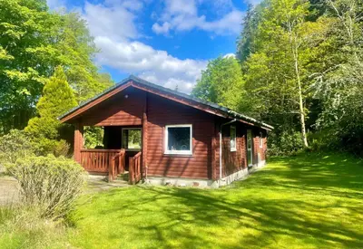 a small wooden cabin in a field of grass at 18 Lamont Lodges in Dunoon
