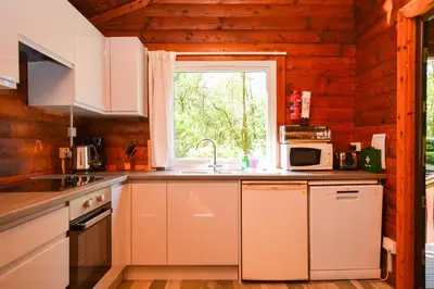 a kitchen with white cabinets and a window and a sink at 18 Lamont Lodges in Dunoon