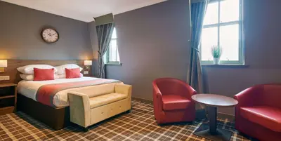 a hotel room with a bed and a red chair at Best Western Glasgow Hotel in Glasgow