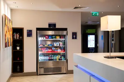 a drink refrigerator in a restaurant with a counter at Holiday Inn Express - Glasgow Airport by IHG in Paisley
