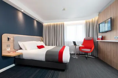 a hotel room with a bed and a red chair at Holiday Inn Express - Glasgow Airport by IHG in Paisley