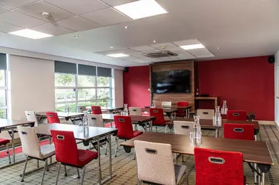 a dining room with tables and red chairs at Holiday Inn Express - Glasgow Airport by IHG in Paisley