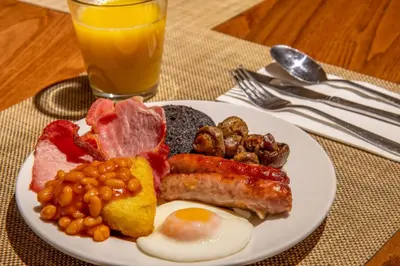 a plate of breakfast food with eggs bacon beans and meat at Britannia Edinburgh Hotel in Edinburgh