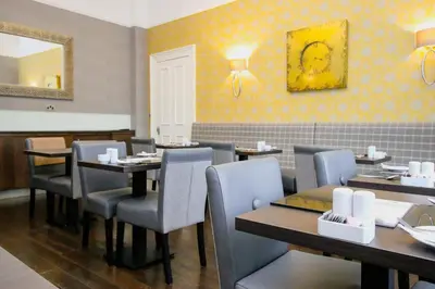 a restaurant with tables and chairs and a mirror at Ambassador Hotel in Glasgow