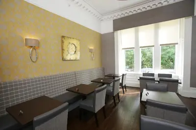 a dining room with tables and chairs and windows at Ambassador Hotel in Glasgow