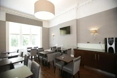 a restaurant with tables and chairs and a large window at Ambassador Hotel in Glasgow