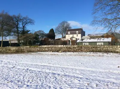 a snow covered field with a house in the background at Garden Studio for Two in Doune