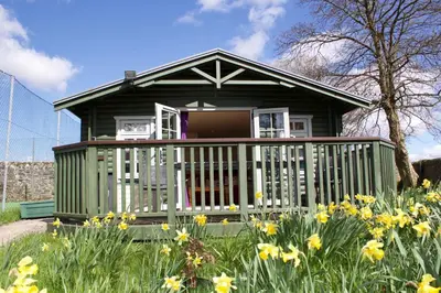a green house with a deck in a field of flowers at Garden Studio for Two in Doune