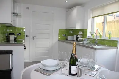 a white kitchen with a bottle of wine and glasses at Alma Villa in Falkirk